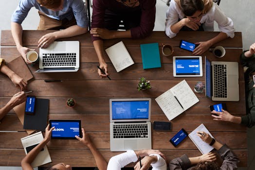 Overhead view of a diverse team in a business meeting using laptops and tablets.